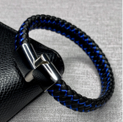 Black and blue braided bracelet with a silver clasp on a textured gray background