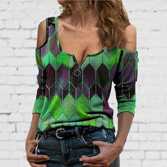 Woman wearing a green and purple geometric patterned top against a white brick wall.