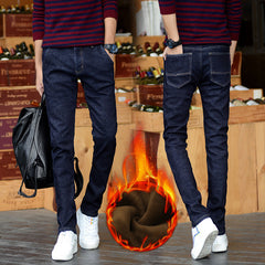 Person wearing dark blue jeans with a fiery effect on a wooden floor background