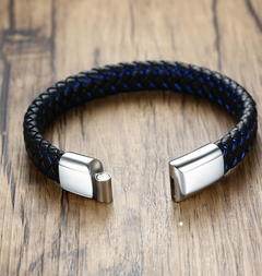 Black and blue braided bracelet with silver clasp on a wooden surface
