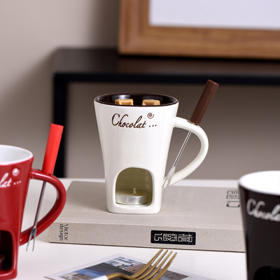 White mug with 'Chocolat' branding on a surface with other mugs and a fork.