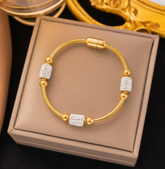 Gold bracelet with diamond accents on a beige box