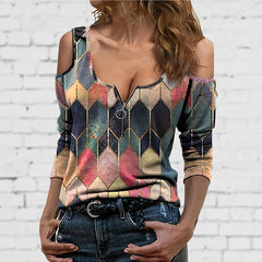 Woman wearing a colorful geometric-patterned sleeveless top against a white brick wall.