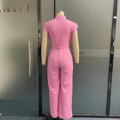 Mannequin wearing a pink jumpsuit in front of a gray door.