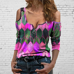 Woman wearing a colorful geometric-patterned top against a white brick wall.