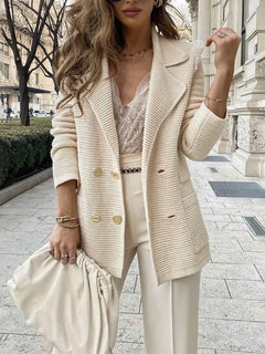 Woman wearing a beige blazer and white outfit on a city street.