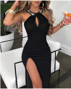 Woman in a black dress with a high slit, holding a drink, in an indoor setting.