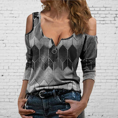 Woman wearing a patterned off-shoulder top against a white brick wall.