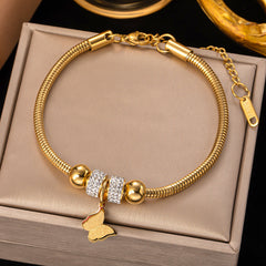 Gold bracelet with a butterfly charm on a beige jewelry box