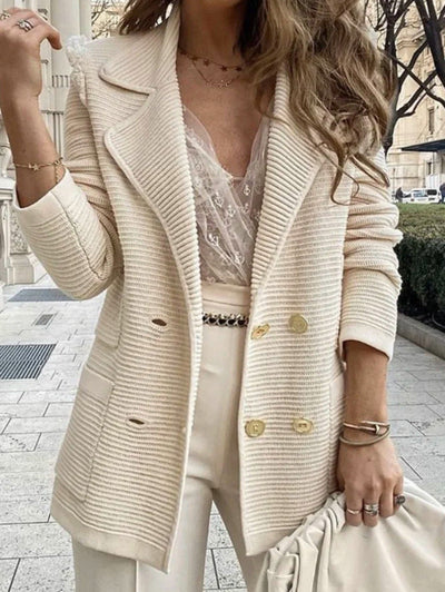 Person wearing a beige coat with gold buttons on a city street.