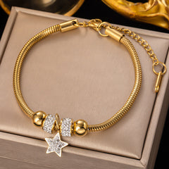 Gold bracelet with star charm on a beige jewelry box