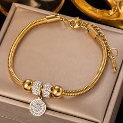 Gold bracelet with decorative beads on a beige surface