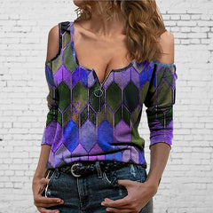 Woman wearing a colorful geometric-patterned top against a white brick wall.